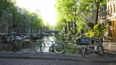 Bulanık bisikletler bir köprüye yaslanıyor ağaçlar ve güneş ışığında bir kanal..