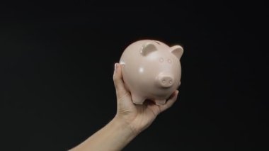 Siyah arka planda pembe kumbara, tasarruf ve mali güvenliği temsil ediyor, münferit nesnelerin yer aldığı yatırım kavramları için ideal..