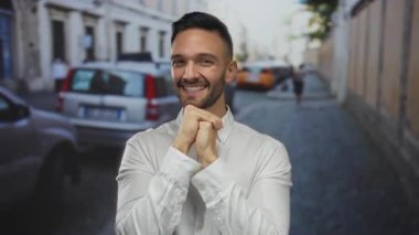 Kalabalık bir şehir caddesinde gülümseyen genç bir adam, canlı bir şehir ortamında şehir hayatının canlı özünü yakalıyor park etmiş arabalarla canlı bir mahallede şehir manzarasını kaplıyor..