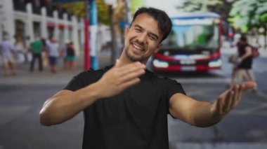 Arka planda bulanık bir otobüsle kalabalık bir caddede gülümseyen ve kendine sarılan İspanyol genç adam..