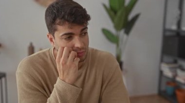 Erkek evde düşünürken elini kaldırır ve İspanyol genç erkek dalgın dalgın dalgın görünür..