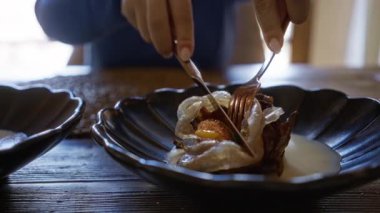 Akdeniz lokantasında yemek tabağında çatal ve bıçak kullanan bir kadını yakın plan çekimde görüyoruz..