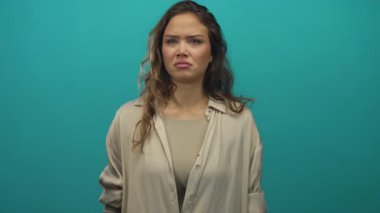 İzole edilmiş yeşil bir zemine karşı elleri kulaklarında rahatsızlık gösteren tarafsız kıyafetler giyen bir kadın hoş olmayan bir sese ya da duruma tepki verdiğini gösteriyor..