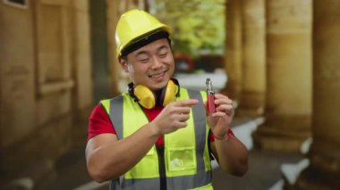 Güvenlik teçhizatlı genç adam eski üniversite binasının içinde kendine güvenle gülümsüyor..