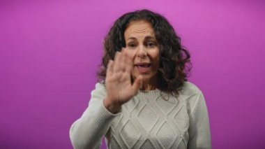 Kadın enerjik bir şekilde mor bir arka plana karşı hareketli, dinamik, izole edilmiş duygusal ifade çerçevesinde kıvırcık saçlarını ve anlamlı jestlerini sergiliyor..