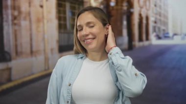 Genç sarışın kadın, şehir caddesinde elleri peekaboo ile gözlerini kapatıyor; neşe ve mutluluk..