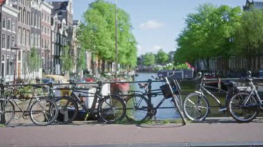 Bisikletler Amsterdam, Hollanda 'nın manzaralı kanalları boyunca sıralanmış, tarihi binalar ve bereketli ağaçlar, canlı bir kentsel atmosfer yaratıyor..