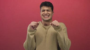 Erkek omuzlarını kaldırır ve arka planda süveter çekerken İspanyol genç erkek gergin ve gergin görünür..