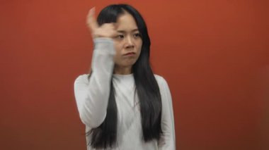 İzole edilmiş kırmızı arkaplan üzerinde iddialı bir şekilde ileri bakan kadın, yoğun ifadeyle aciliyet ya da yönü ima ederek çerçevede baskın bir görsel etki yaratıyor.