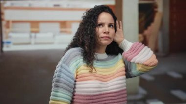 İnşaat alanında renkli bir kazak giyen İspanyol kadın kısmen inşa edilmiş bir evde dikkatlice dinlerken merakını dile getiriyor..