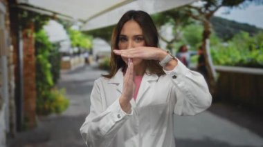 Şehir sokaklarında laboratuvar önlüğü giyen bir kadın, arka planda ağaçlarla bir mola ya da duraklama olduğunu gösteriyor..