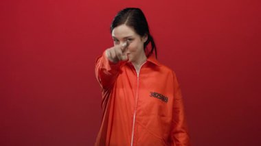 Turuncu hapishane tulumlu kadın neşeli noktalar ve hareketler canlı kırmızı arka planda büyüleyici bir eğlence teması yaratıyor..