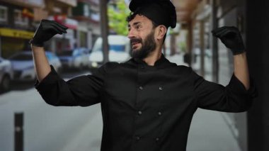 Siyah üniformalı ve eldivenli İspanyol şef, arka planda binalar ve araçlarla kalabalık bir caddede dikiliyor..