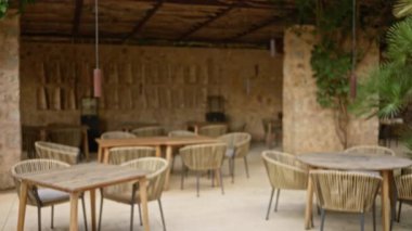 Taştan duvarları ve hasır sandalyeleri olan ıssız bir teras kırsal bir Akdeniz restoranı atmosferi yaratıyor.