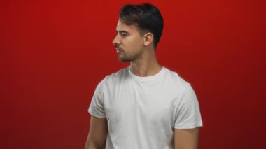 Beyaz gömlekli genç adam, izole edilmiş kırmızı arka plana karşı duruyor. Basitlik ve canlı renk karşıtlığına vurgu yaparak düşünceli bir ifade sergiliyor..