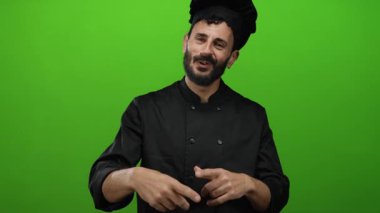 Parlak yeşil bir altyapısı olan, siyah üniformalı ve şapka takan, sakallı İspanyol aşçı şefi..