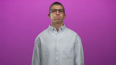 Gözlüklü bir adam canlı pembe bir arka plana karşı komik bir yüz yapar çizgili bir gömlek giyerek oyuncu ve ilginç bir ifade sergiler.