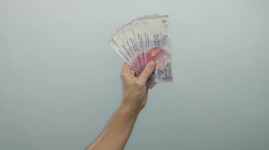 Beyaz tenli erkek, elinde Arjantin pezosu bulunan banknotlar, para ve finans konularının altını çiziyor.