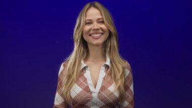 Sarı saçlı kadın fotoğraf stüdyosunda el sallayan desenli gömlek giyen; arkadaşlığı sıcak karşılayan.