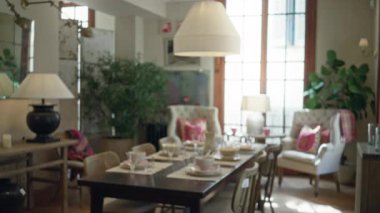 Sıcak oturma odası, bulanık yemek düzeniyle ve lüks sandalyelerle sıcak bir ev atmosferi yaratarak, yumuşak ışıklandırma ve nötr, davetkar bir dekor yaratıyor..