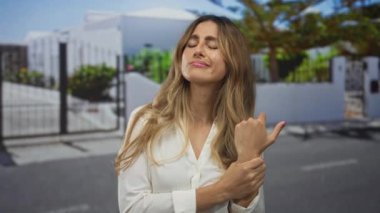 Banliyöde acı dolu bir ifadeyle uzun dalgalı saçları olan genç sarışın kadın, acı verici bir rahatsızlık..