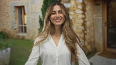 Kadın, avuç içlerini taştan avluya uzatarak el büyüklüğünde jest yapıyor..