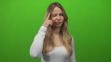 Uzun kollu beyaz kollu sarışın kadın, stüdyoda işaret parmağı olan tapınağa dokunuyor..