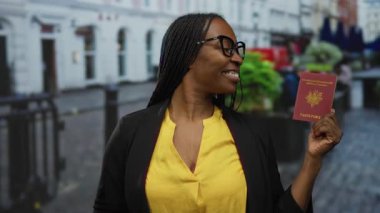 Şehirdeki sokak ortamında Fransız pasaportu taşıyan kadın gülümsüyor, seyahat hazırlığı ve enerjik enerji ve kendine güvenle uluslararası bağlantılar sergiliyor..