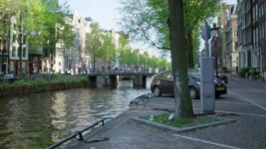 Hollanda 'da çözünmüş köprü ve geleneksel Hollanda mimarisi ile Amsterdam Kanalı' nın bulanık görüntüsü, odak dışı manzarada kentsel bir manzara sergiliyor.