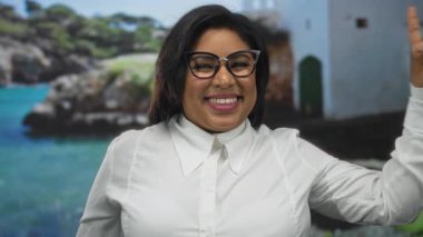 Sahilde güvenle gülümseyen bir kadın parmaklarını yukarı kaldırarak güzel bir kumsal zeminine doğru işaret ediyor..