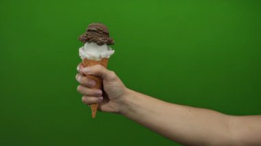 Adamın eli çikolatalı vanilyalı dondurma külahını canlı yeşil arka plana karşı tutarak yazın izole edilmiş lezzetli tatlı kavramını tasvir ediyor..