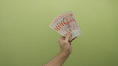 Sarı bir zemin üzerinde Singapur dolar tutan bir adam, banknotlar hayranı sergilenen izole para üzerinde odaklanarak sergilenen.