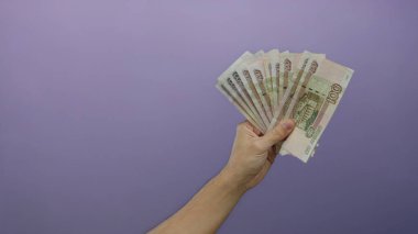 Mor arka planda Rus rublesi tutan adam izole bir ortamda finansal refah ve iş fırsatları sergiliyor..