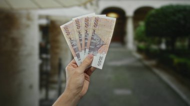İzlanda Krona banknotları tutan bir adam, şehir merkezinde gündüz vakti para birimini açık havada gösteren beyaz elle finans kavramını resmediyor..