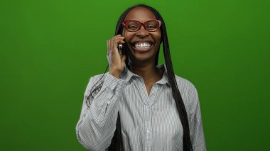 Cep telefonuyla konuşan bir kadın, izole edilmiş yeşil arka planda neşeli bir iletişim sergiliyor..
