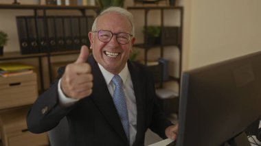 Takım elbiseli son sınıf öğrencisi, ofisteki bilgisayarda onaylıyor. Profesyonel iş ortamında güven ve memnuniyet gösteriyor..