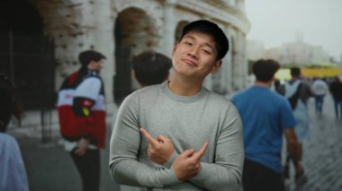Arka planda bulanık bir sokak sahnesiyle tarihi Roma Stadyumu 'nun dışında güvenle poz veren genç Çinli bir adam..