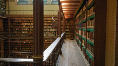 Bokeh efektiyle tarihi bir kütüphanenin içini bulanık görmek, eski kitapların raflarının altını çizmek ve sakin, bilimsel bir atmosferde dolambaçlı bir merdiven..