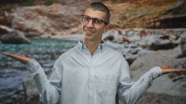 Sahilde gözlüklü ve çizgili gömlekli bir adam rahat bir deniz sahnesi sergiliyor. Huzurlu, neşeli ve davetkar bir atmosfer sergiliyor..