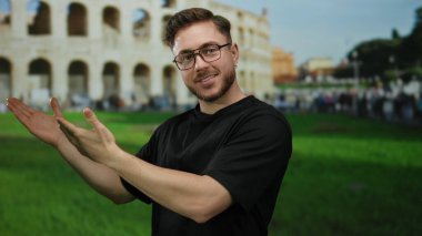 Roma Kolezyumu 'nun önünde gülümseyen ve sunan sakallı genç adam güneşli gökyüzünün altında tarihi Roma' nın özünü yakalıyor..