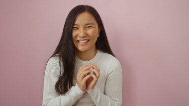 İzole edilmiş pembe arka planda güzel gülümseyen genç Çinli kadın doğal çekicilik ve yetişkin Asyalı cazibesini sergiliyor..