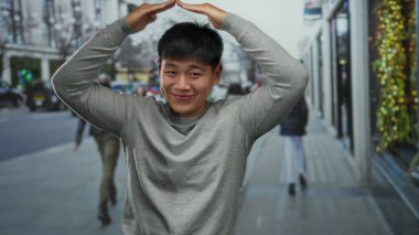 Genç adam şehrin bir caddesinde mutlu bir şekilde dikiliyor, bir şehir zeminine karşı Çin mirasını sergiliyor, açık havada keyif ve kültür anı yakalıyor..