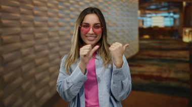 Otel lobisinde parmaklarını kulise uzatan pembe gözlükler takan, günlük kıyafetlerle gülümseyen, boş vakitler ve kendine güvenen bir kadın..