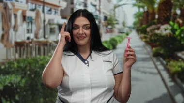 Güneşli bir günde palmiye ağaçlarıyla kaplı bir caddede pembe jilet tutan kadın, şehir hayatı ve kendine güveni somutlaştırıyor..