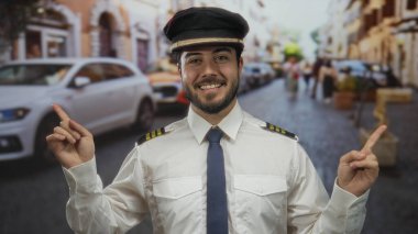 Kaptan üniformalı İspanyol bir adam. Açık havada, her iki yönde de şapka noktaları var. Bulanık arabaları ve insanları var..