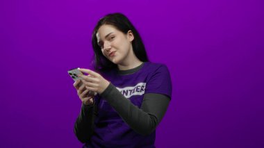 Mor tişörtlü akıllı telefonu canlı mor arka plana karşı kullanan kadın modern teknoloji meraklısı bir görüntü sergiliyor. Kamu hizmetinin özünü yakalıyor..