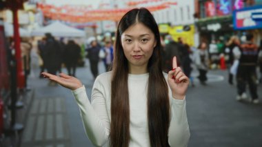 Hayır diyen bir kadın, arka planda canlı şehir hayatı ve kültürel unsurlarla çevrili, Çin 'deki işlek şehir caddesinde açık avuçla işaret ediyor..