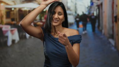 Bir kadın restoran terasında güvenle poz veriyor, şık giyinmiş sokak arkaplanı ile şehir yaşamını gösteriyor..