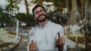 Parkta sakallı İspanyol bir adam yeşil ağaçların arasında meydan okuyarak doğal ortamda cesur bir ifade yaratabilir..