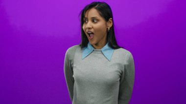 Parlak mor arka plana karşı şaşkınlığını ifade eden bir kadın. Duygularını ve ruh halini dışa vurguluyor. Genç, enerjik Latin özelliklerini ortaya koyuyor.